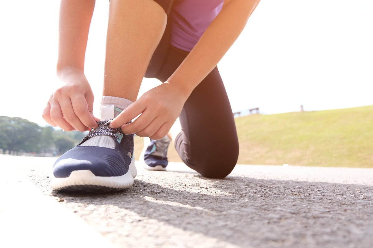 Active healthy woman tying running shoes,  jogging runner health